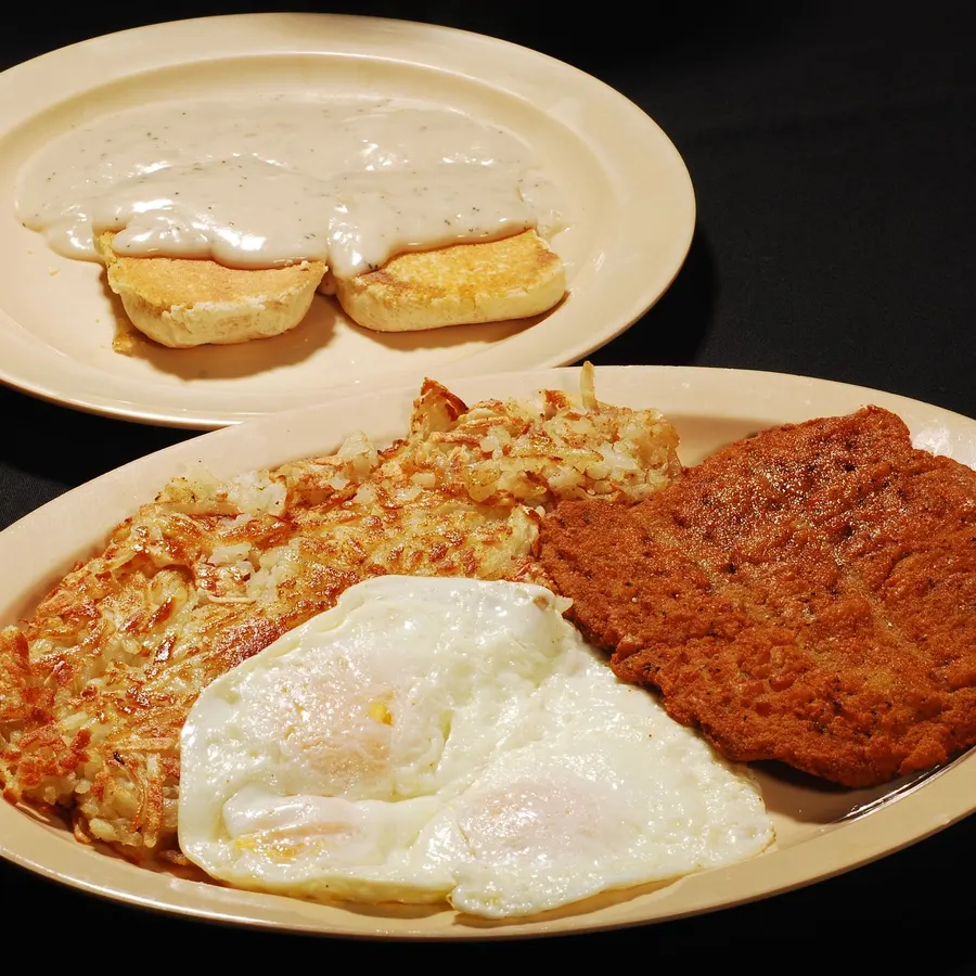 Chicken fried steak with two eggs and hash browns, biscuits and gravy alongside