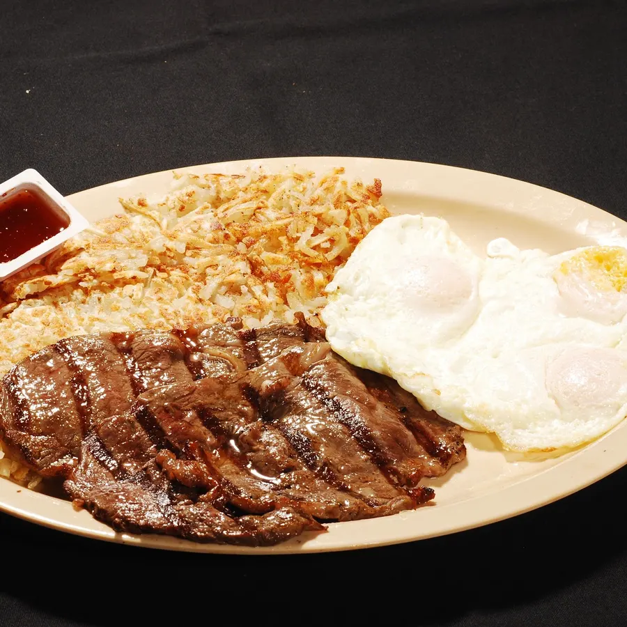 Carne asada with two eggs, home style hash browns and salsa on a white plate
